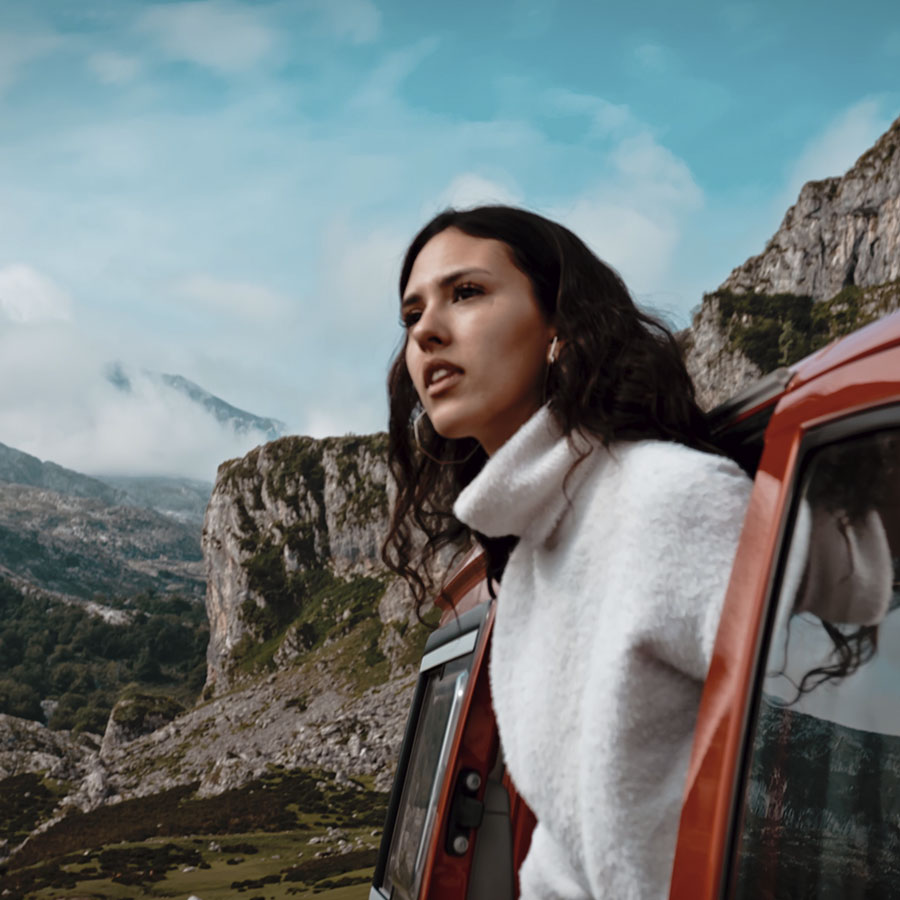 Mujer saliendo de furgoneta camper en la montaña